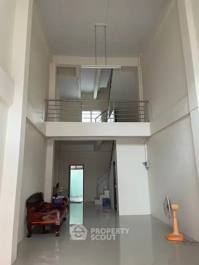 Spacious modern living room with high ceiling and mezzanine, featuring sleek design and ample natural light.