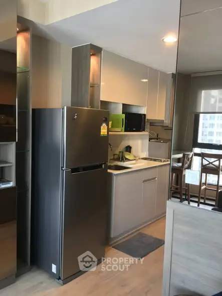 Modern kitchen with sleek cabinetry and stainless steel fridge in a contemporary apartment.