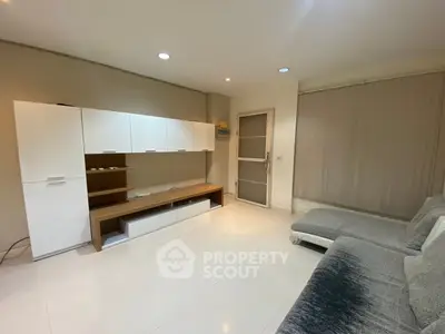 Modern living room with sleek white cabinets and cozy gray sofas