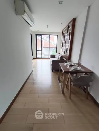 Modern living room with dining area and balcony access, featuring sleek furniture and natural light.