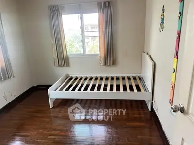 Spacious bedroom with wooden floors and large window for natural light