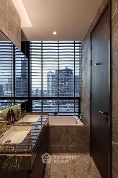 Luxurious bathroom with city view, featuring dual sinks and a modern bathtub.