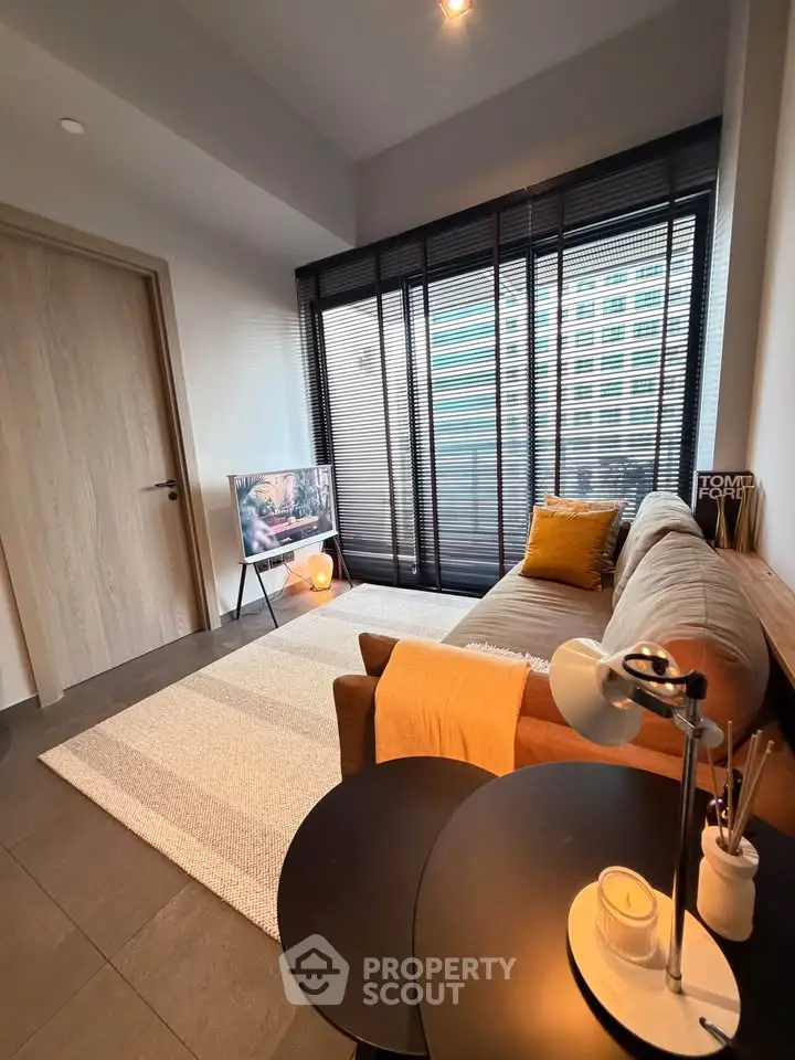 Modern living room with cozy sofa, stylish decor, and large window with blinds, perfect for relaxation.