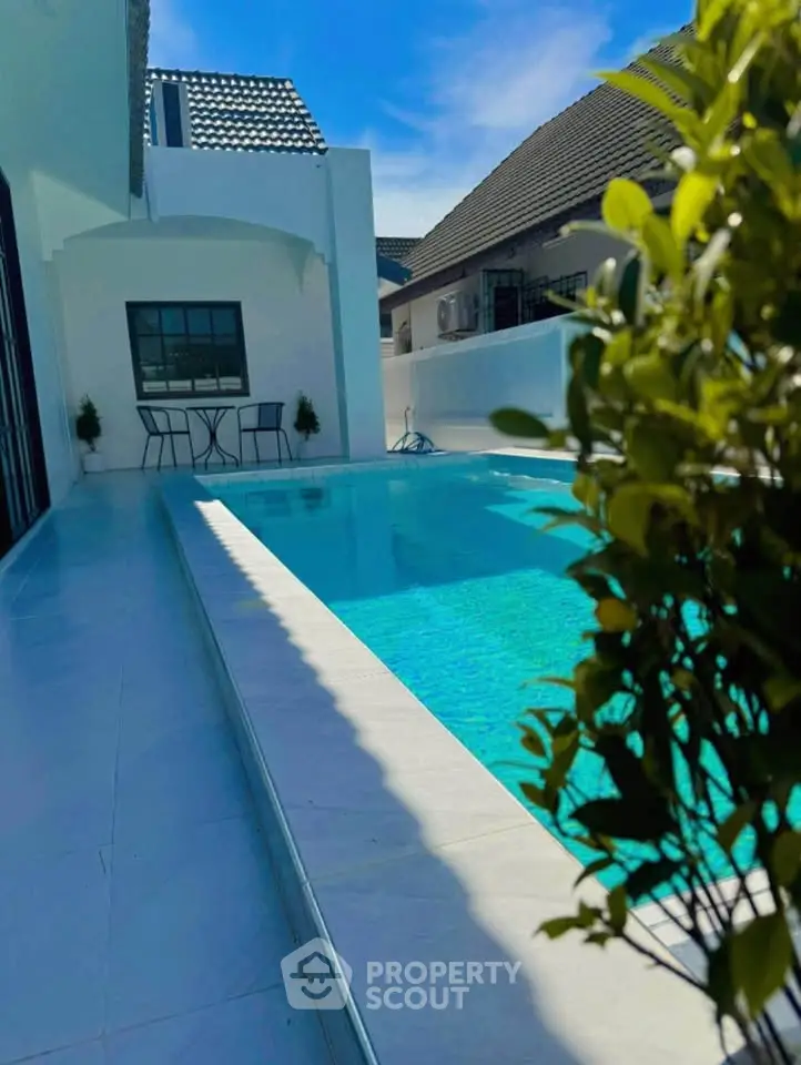Luxurious modern home with a stunning private pool and elegant outdoor seating area.