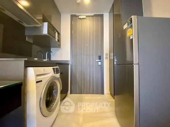 Modern kitchen with washing machine and sleek appliances in compact layout.
