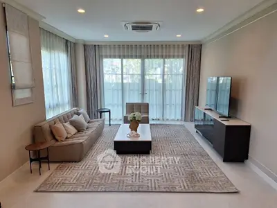 Elegant living room with modern decor, large windows, and cozy seating area.