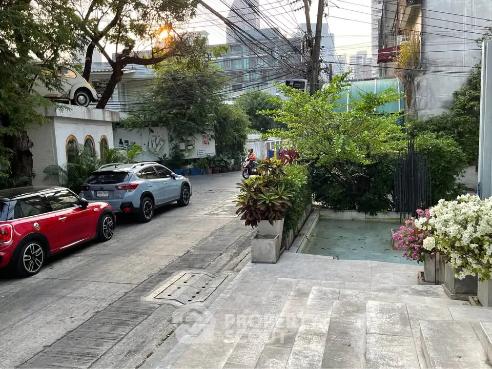 Charming urban street view with lush greenery and parked cars, perfect for city living.