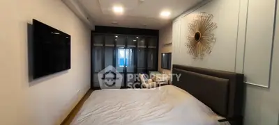 Modern bedroom with stylish decor and large TV, featuring a comfortable bed and sleek wardrobe.