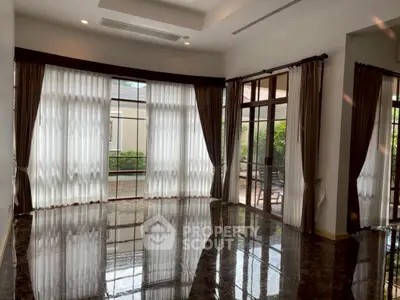 Spacious living room with large windows and elegant curtains, featuring glossy marble flooring and garden view.