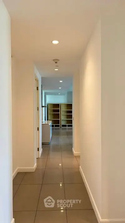 Spacious hallway leading to a bright living area with modern shelving, perfect for contemporary living.