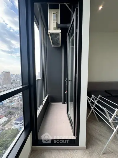Modern high-rise apartment with narrow balcony offering stunning city views.