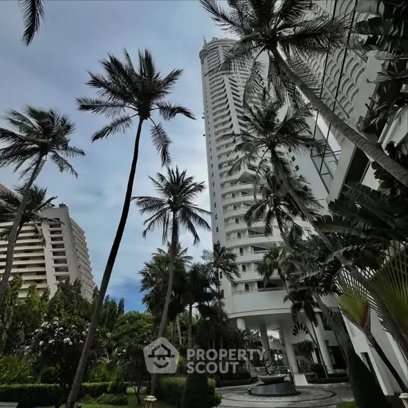 Stunning high-rise building surrounded by lush palm trees and landscaped gardens, offering a luxurious urban oasis.