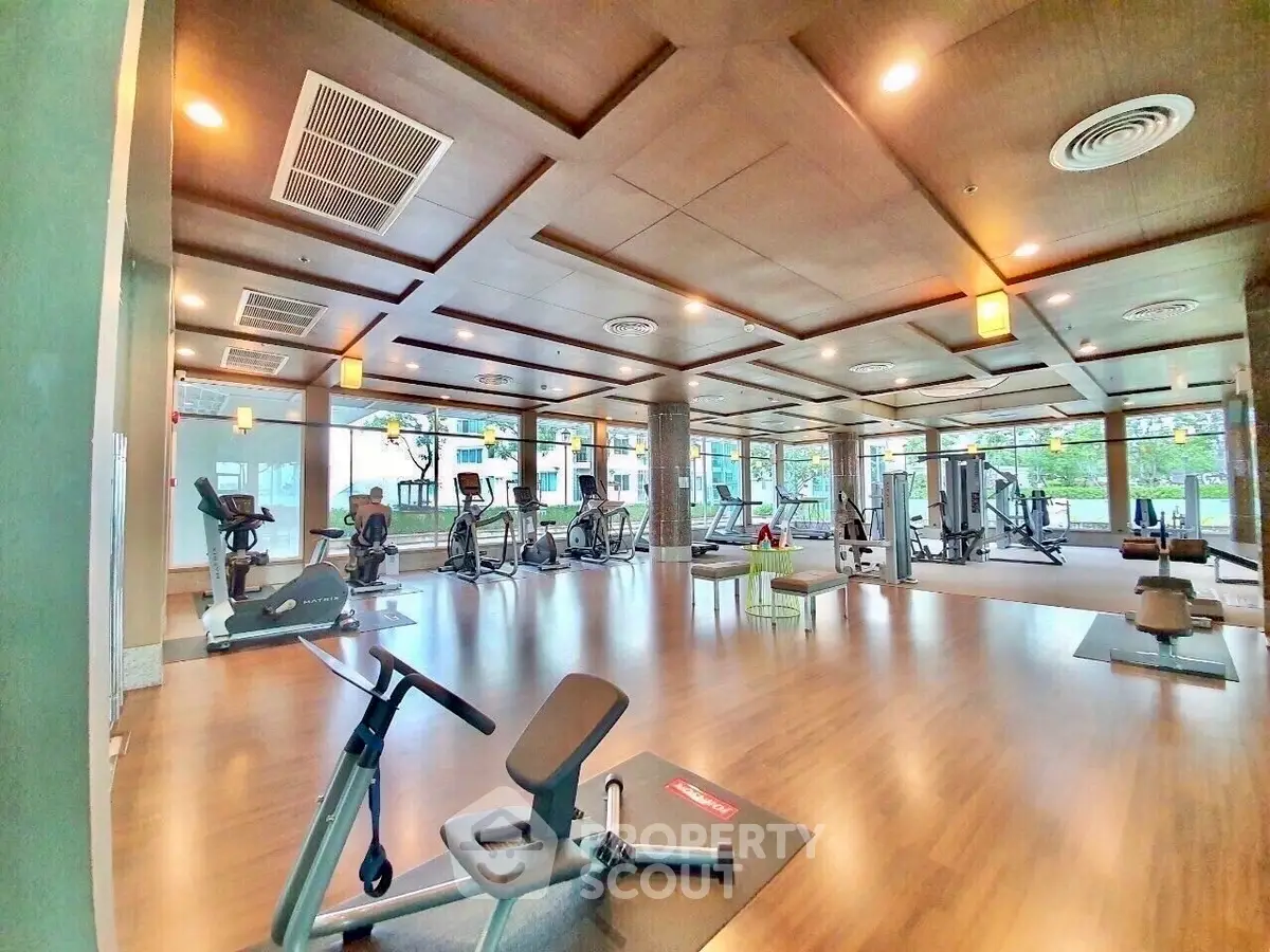 Spacious modern gym with state-of-the-art equipment and wooden flooring.
