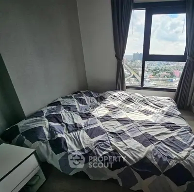 Cozy bedroom with city view, featuring modern decor and large window for natural light.