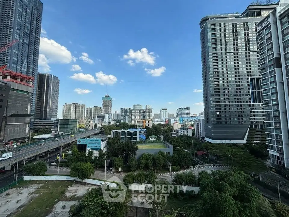 Stunning cityscape view from a high-rise building with lush greenery and clear blue skies.