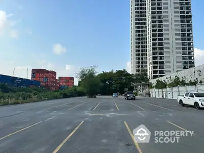 Spacious parking area beside modern high-rise building with clear sky view