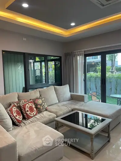 Spacious living room with cozy sectional sofa and large windows overlooking garden.