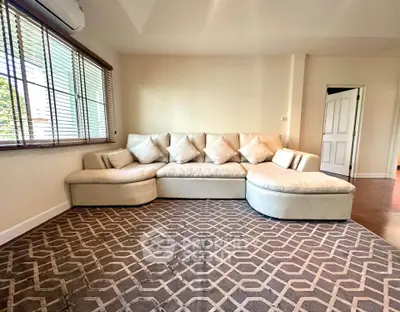 Spacious living room with elegant L-shaped sofa and large window, perfect for relaxation and entertaining.