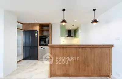 Modern kitchen with wooden cabinetry, sleek appliances, and stylish pendant lighting.