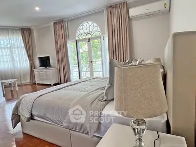 Elegant bedroom with large windows and stylish decor, featuring a cozy bed and modern amenities.