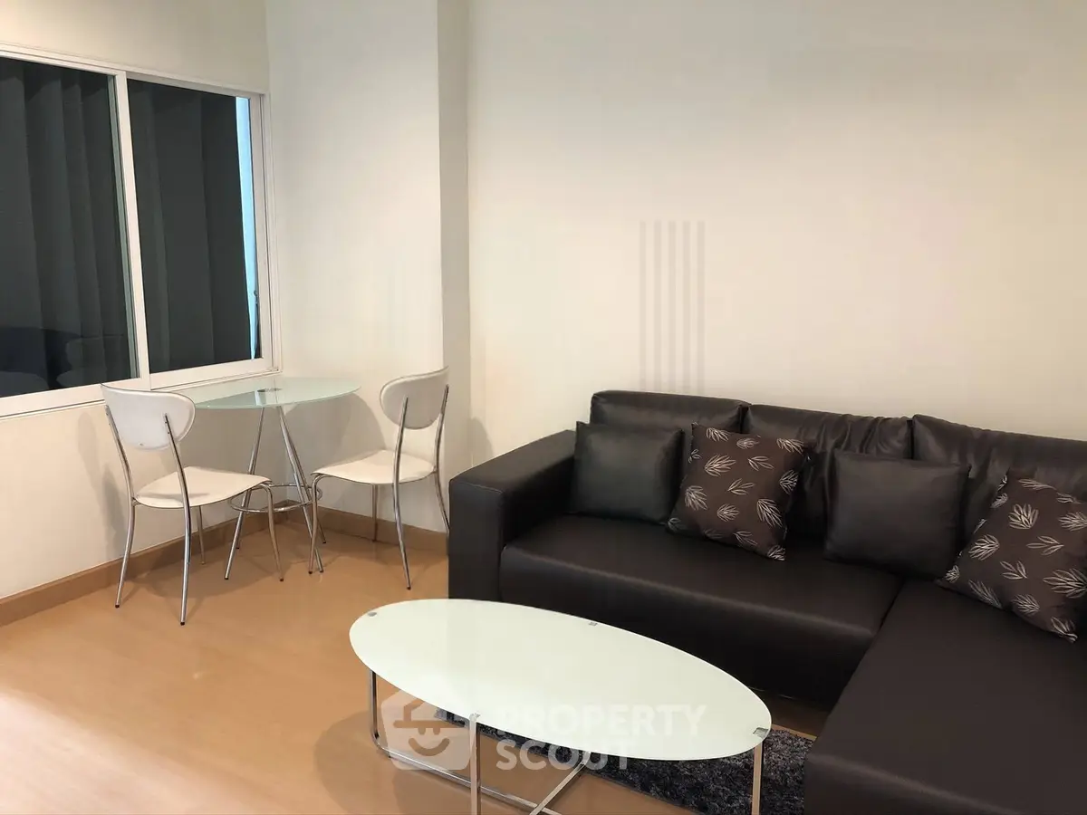 Modern living room with sleek black sofa and glass coffee table, perfect for urban living.
