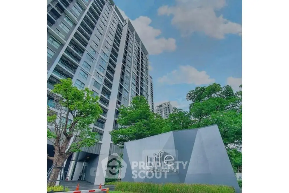 Modern high-rise building with lush greenery and clear blue sky
