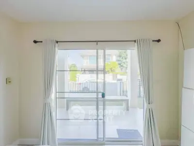 Bright living room with sliding glass doors leading to a spacious patio and garden view.