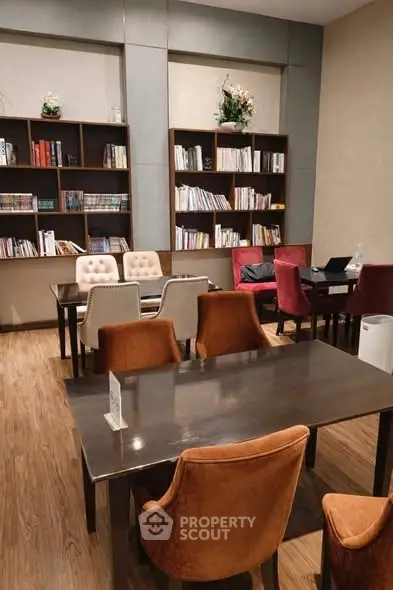 Elegant library with cozy seating and wooden bookshelves in modern real estate setting.