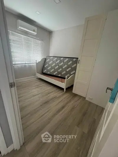 Cozy bedroom with wooden flooring and natural light, featuring a daybed and air conditioning.