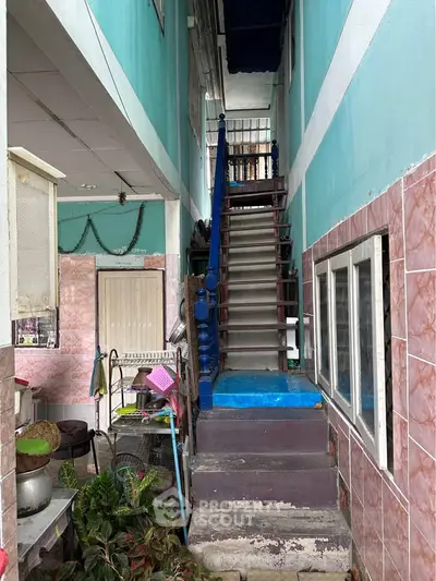 Narrow alleyway with staircase in vibrant urban setting, showcasing unique architectural charm.