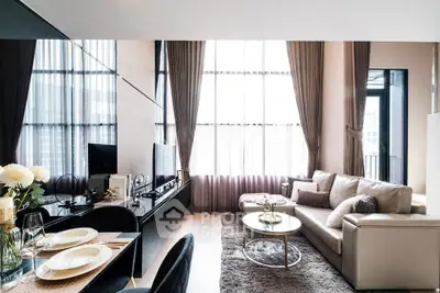 Luxurious modern living room with high ceilings, elegant decor, and large windows offering abundant natural light.