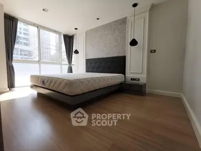 Spacious modern bedroom with large windows and stylish decor in urban apartment.