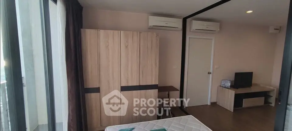 Modern bedroom with large mirror, air conditioning, and stylish wooden furniture.