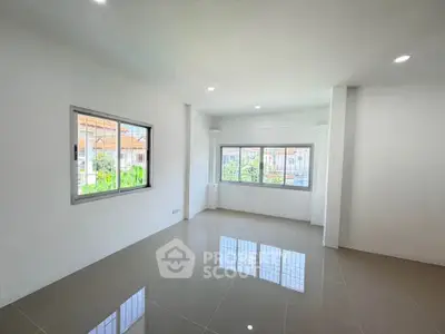 Spacious and bright living room with large windows and glossy tiled floor