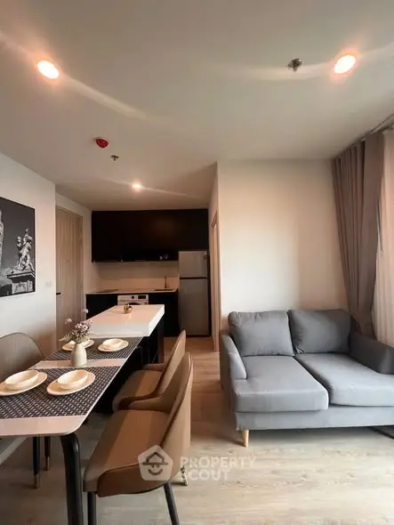 Modern open-plan living room with stylish furniture and kitchen area in a contemporary apartment.
