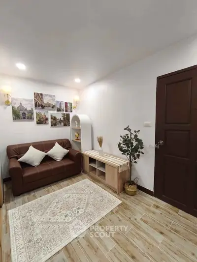 Cozy living room with brown sofa, decorative wall art, and wooden flooring for a warm ambiance.