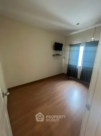 Spacious empty room with wooden flooring and wall-mounted TV, ideal for customization.