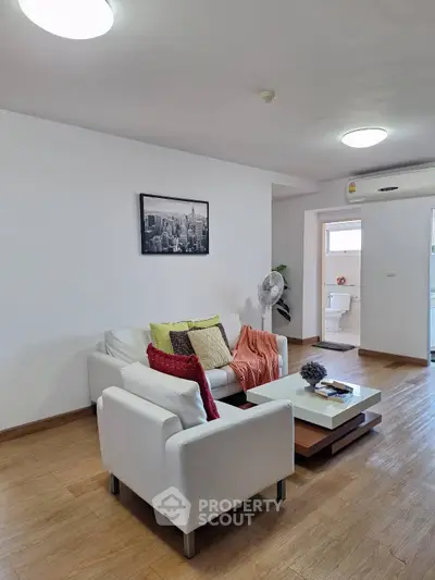 Modern living room with stylish white furniture and wooden flooring