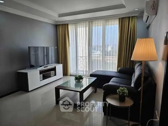 Modern living room with sleek furniture and large windows offering city views.