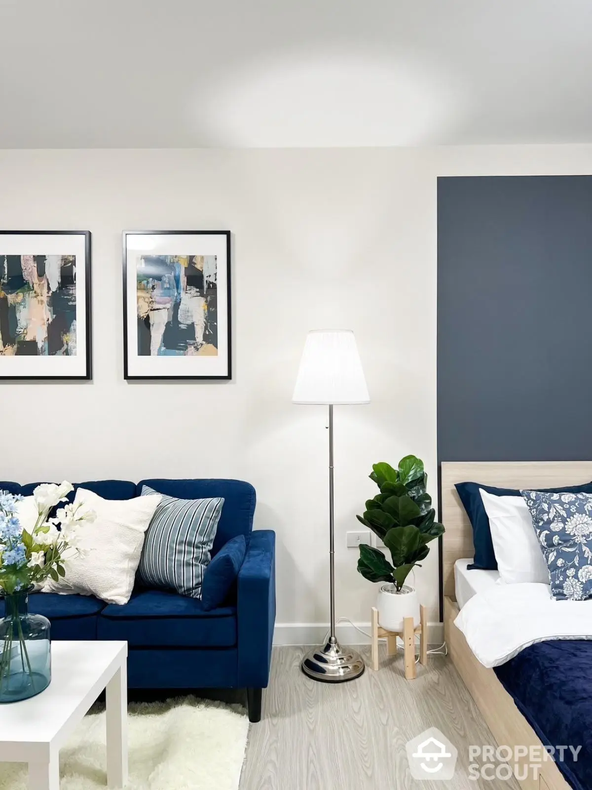 Modern living room with stylish blue sofa and cozy bedroom area, perfect for urban living.