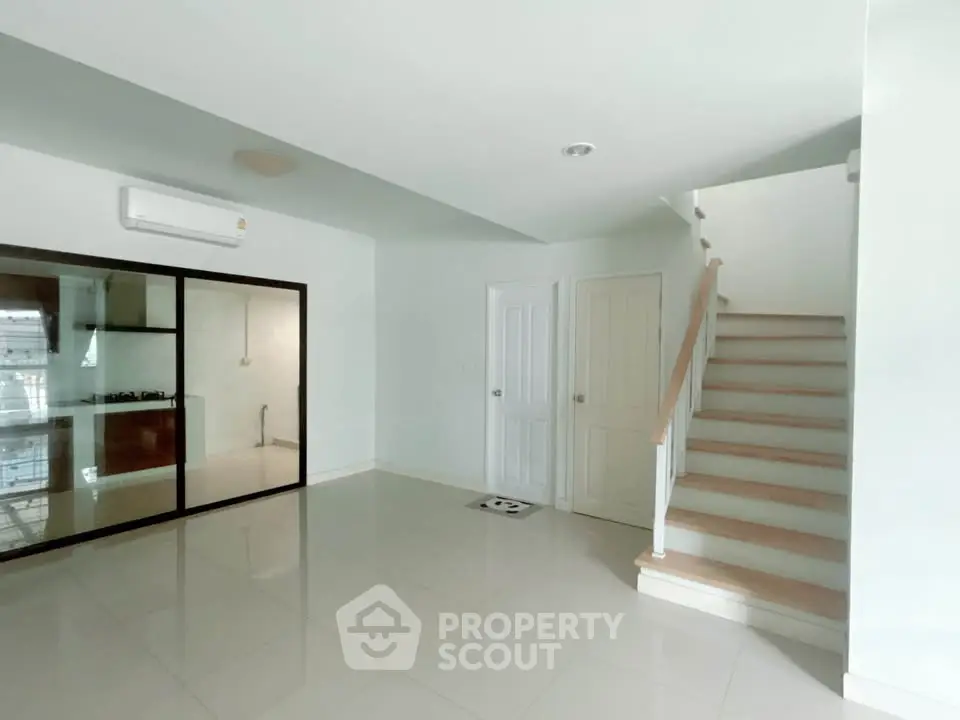Spacious modern living room with staircase and glass kitchen partition