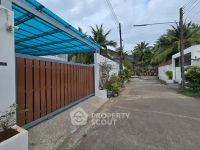 Charming residential entrance with lush greenery and modern gate design.