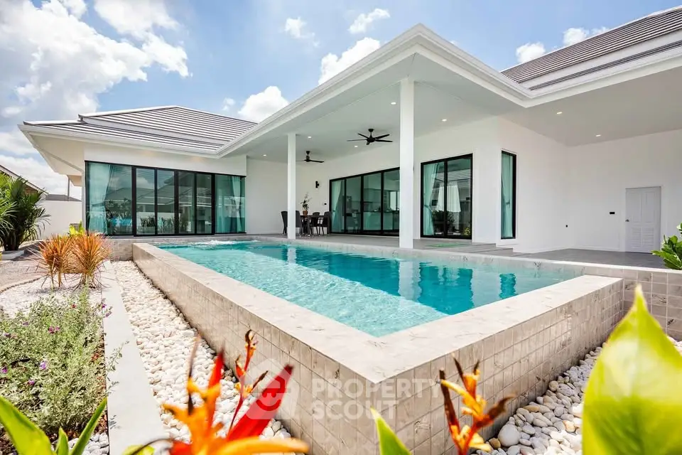 Luxurious modern villa with private pool and elegant landscaping under a clear blue sky.
