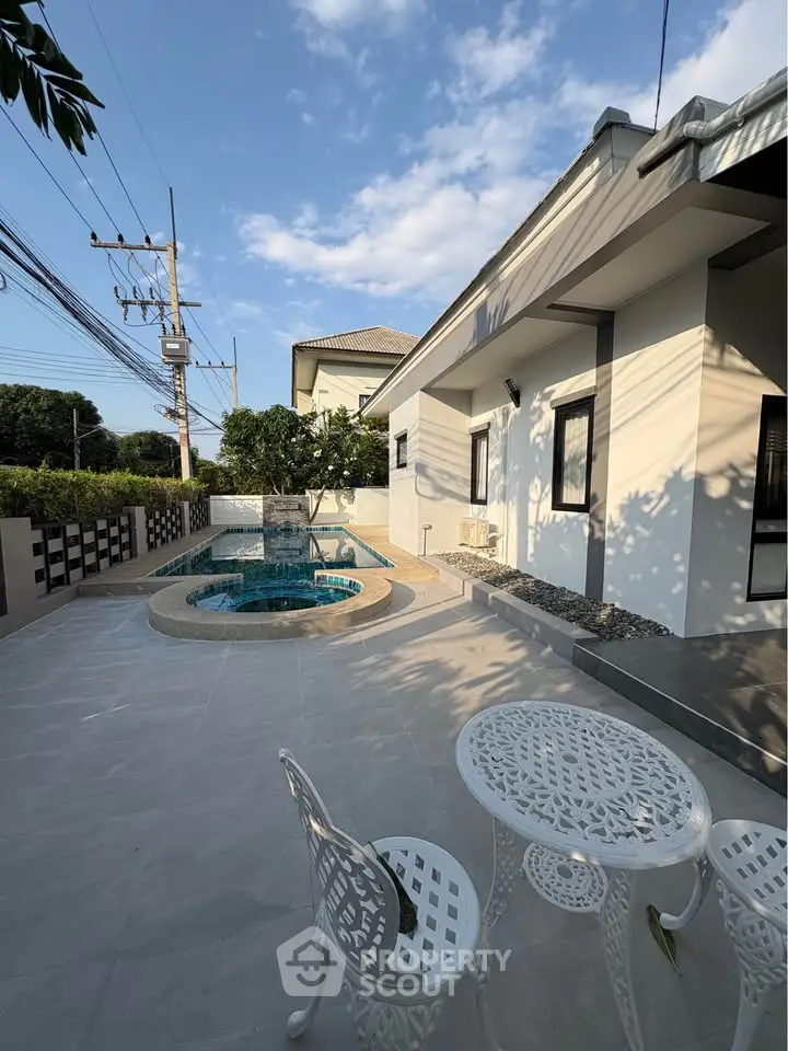 Modern home exterior with private pool and stylish patio furniture under a clear blue sky.