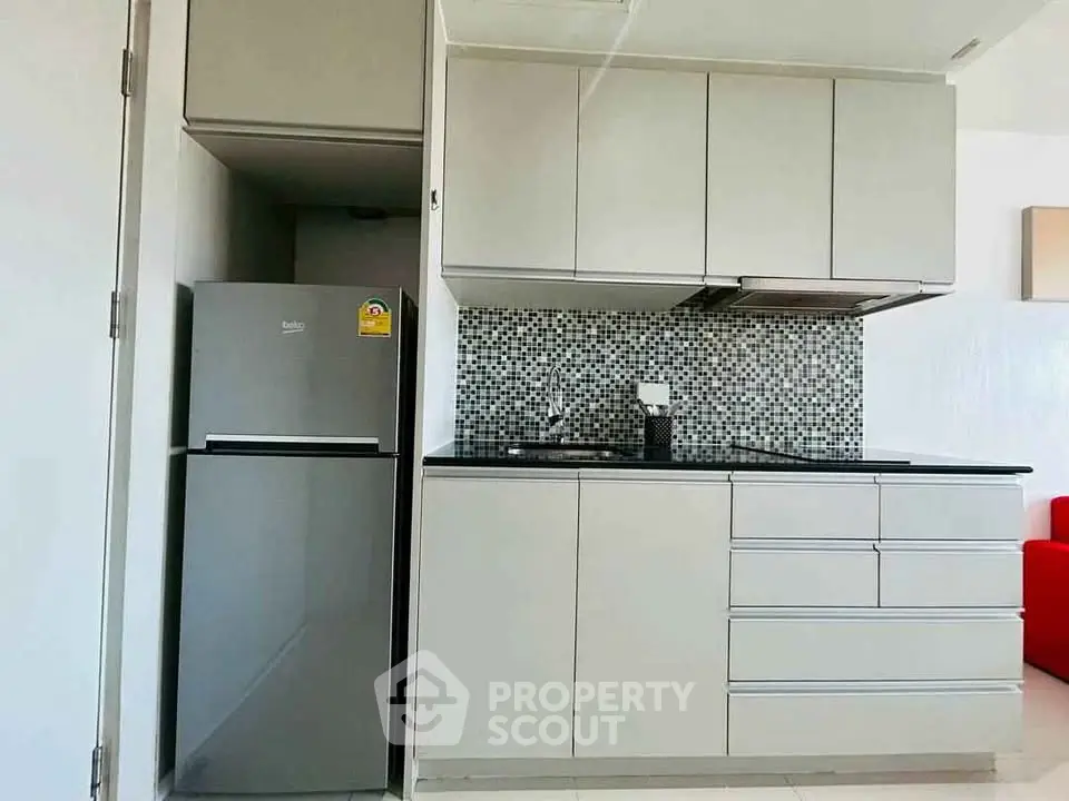 Modern kitchen with sleek cabinetry and mosaic backsplash in a stylish apartment.