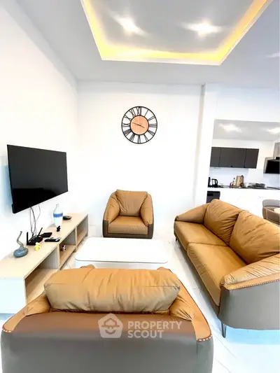 Modern living room with stylish furniture and open kitchen layout, featuring elegant lighting and contemporary decor.