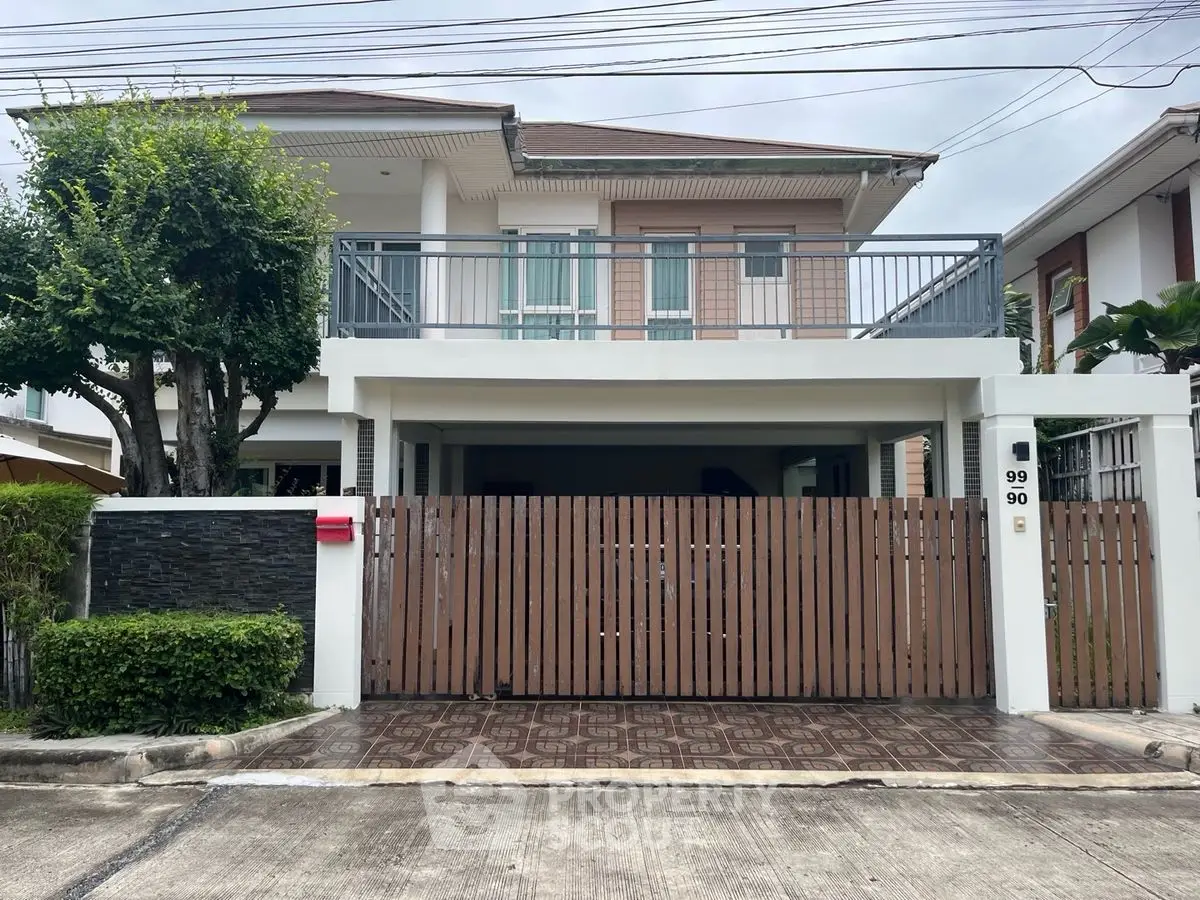 Modern two-story house with gated entrance and balcony in suburban neighborhood.