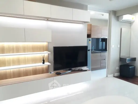 Modern living room with sleek TV unit and open kitchen view.