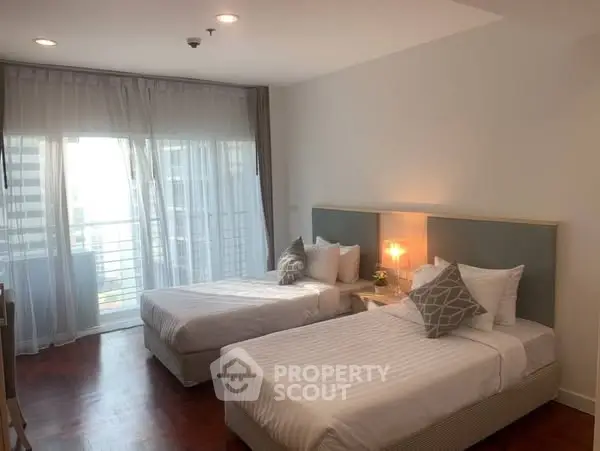 Spacious bedroom with twin beds and balcony access in modern apartment