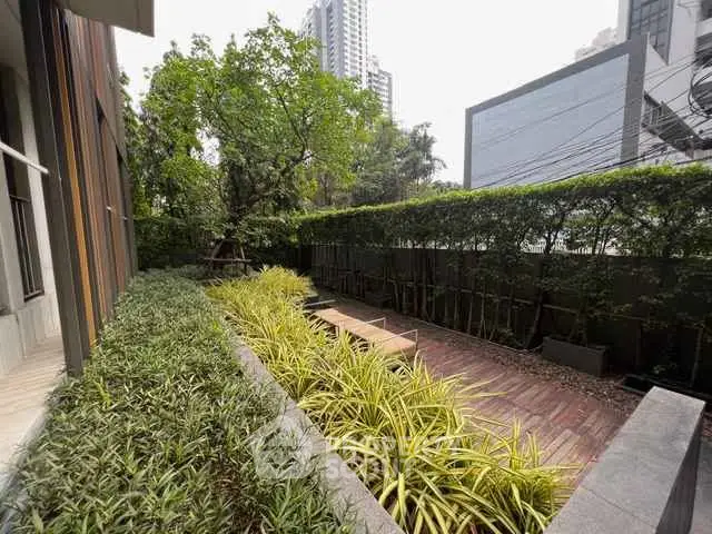 Modern urban garden with lush greenery and wooden deck in city setting